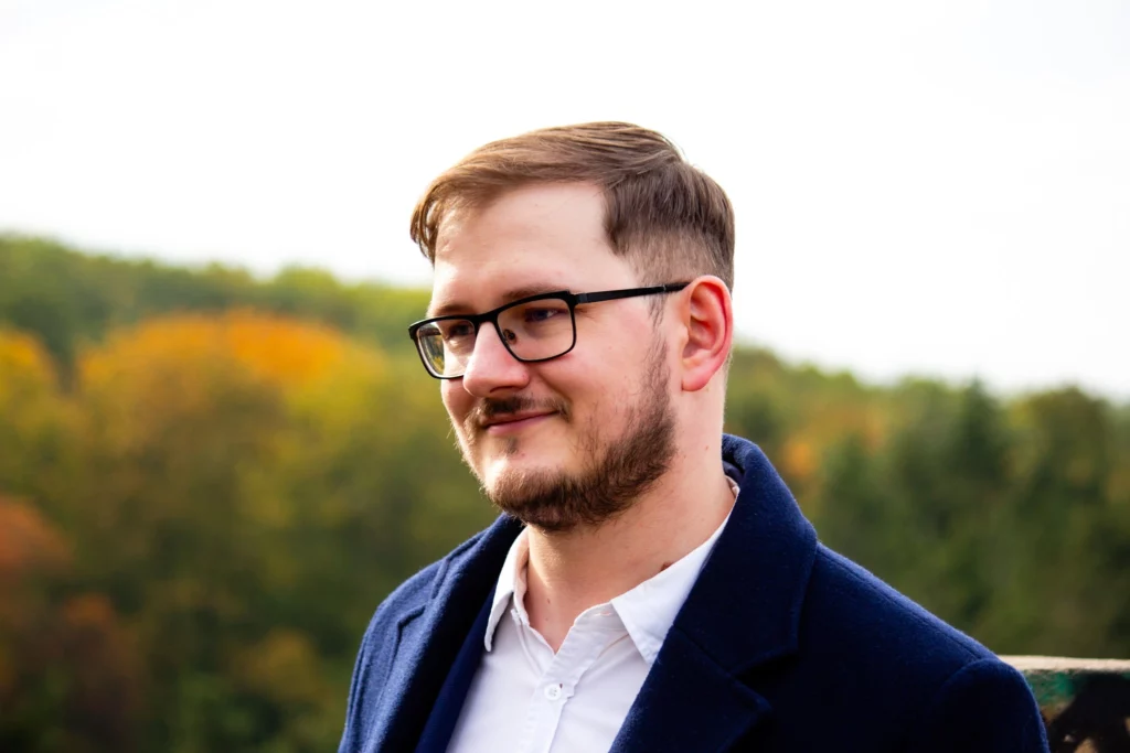 Portrét Marka Krásného v obleku v lesním prostředí s pohledem vlevo